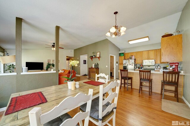 dining space with baseboards, light wood finished floors, and ceiling fan with notable chandelier