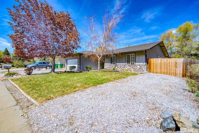 single story home with a front lawn, fence, stone siding, gravel driveway, and an attached garage