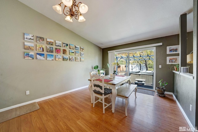 dining room featuring baseboards, lofted ceiling, wood finished floors, and a chandelier