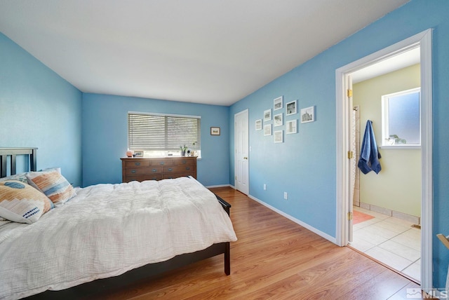 bedroom with baseboards, ensuite bathroom, and wood finished floors