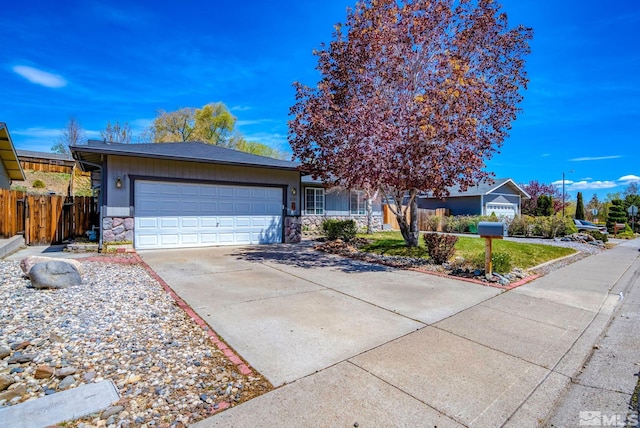 ranch-style house with fence, an attached garage, driveway, and stone siding