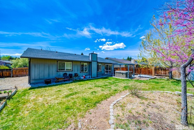 rear view of property with a hot tub, a yard, a fenced backyard, and a patio area