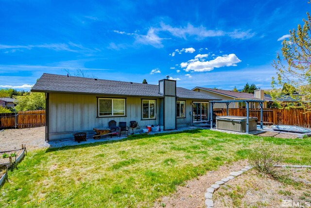 back of property with a fenced backyard, a hot tub, and a patio area