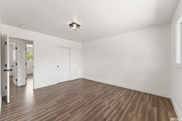 unfurnished bedroom featuring baseboards, dark wood finished floors, and a closet