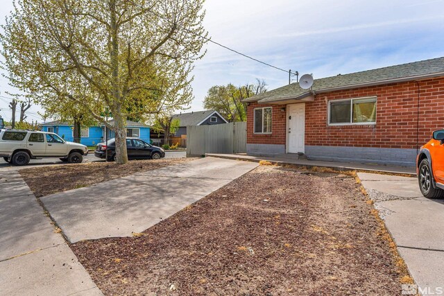 view of front of property with roof with shingles, fence, concrete driveway, and brick siding