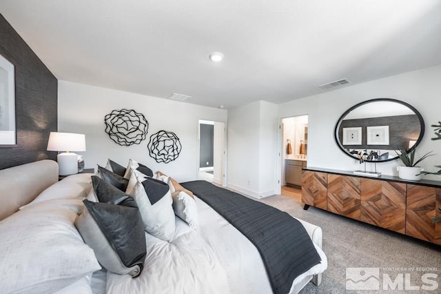 bedroom with baseboards, light colored carpet, connected bathroom, and visible vents