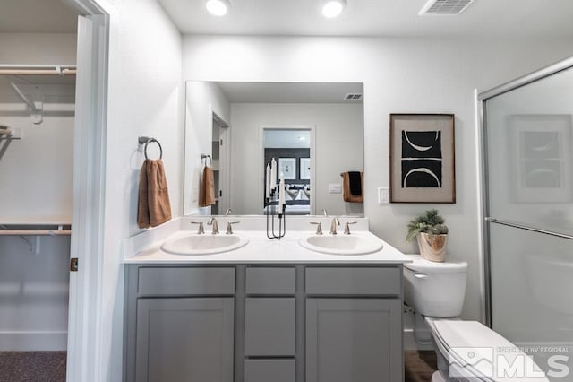 bathroom featuring double vanity, a sink, visible vents, and toilet
