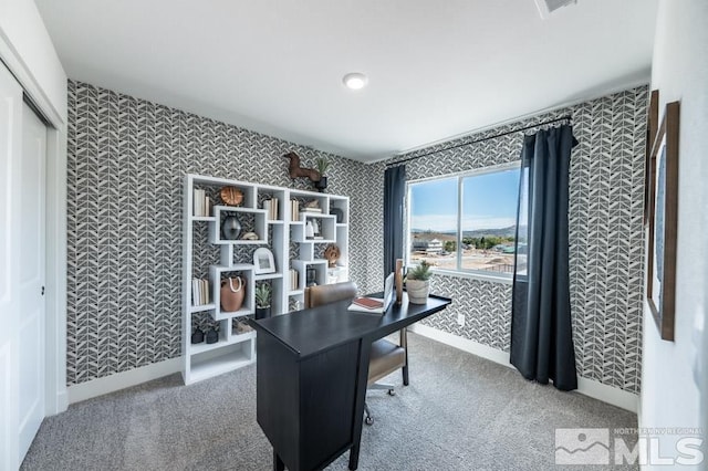 carpeted home office featuring wallpapered walls and baseboards