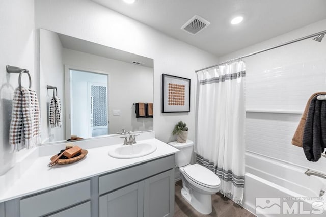full bath with visible vents, vanity, wood finished floors, shower / bath combination with curtain, and toilet