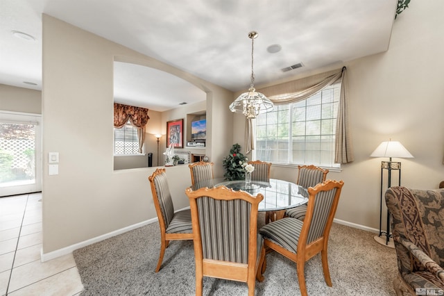 tiled dining space featuring baseboards, arched walkways, a notable chandelier, and visible vents