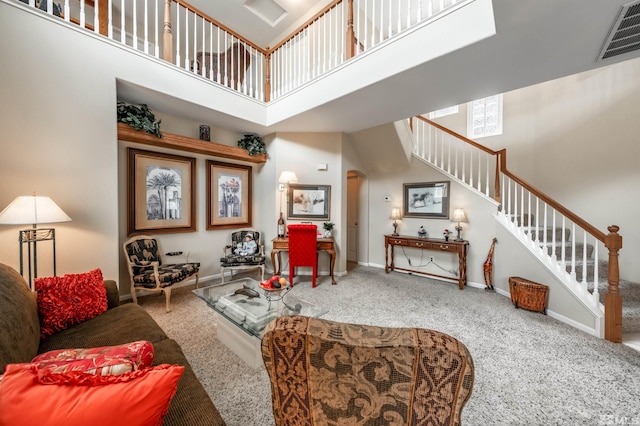 carpeted living room featuring a towering ceiling, visible vents, arched walkways, baseboards, and stairs