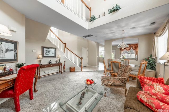 carpeted living area featuring visible vents, baseboards, a notable chandelier, and stairway