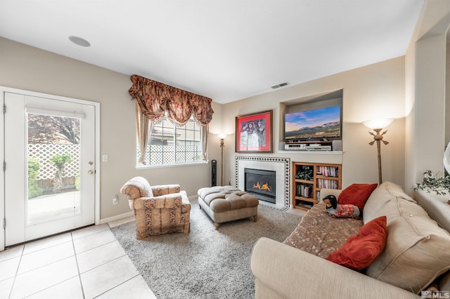 living room with visible vents, plenty of natural light, tile patterned flooring, and a glass covered fireplace