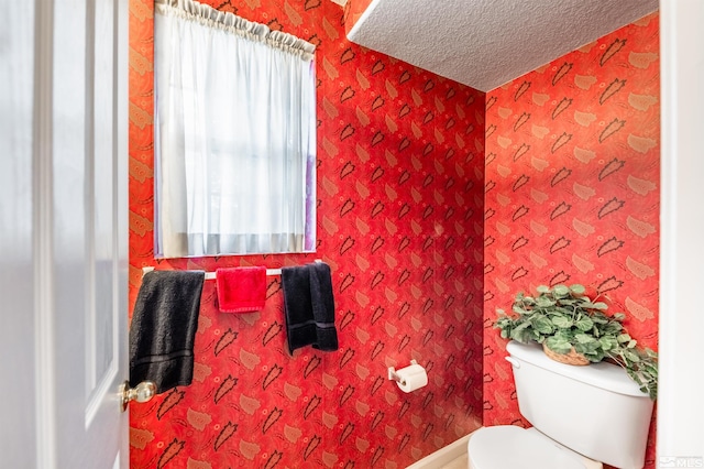 bathroom featuring a textured ceiling, toilet, and wallpapered walls