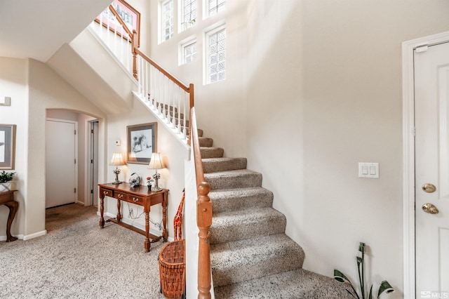 stairs featuring arched walkways, carpet, and a towering ceiling