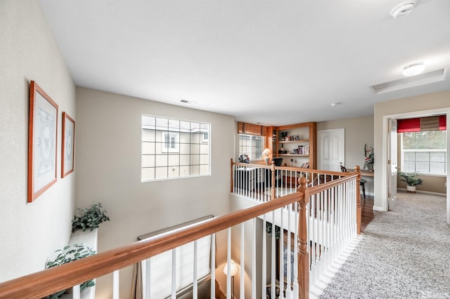 corridor with carpet floors, baseboards, an upstairs landing, and attic access