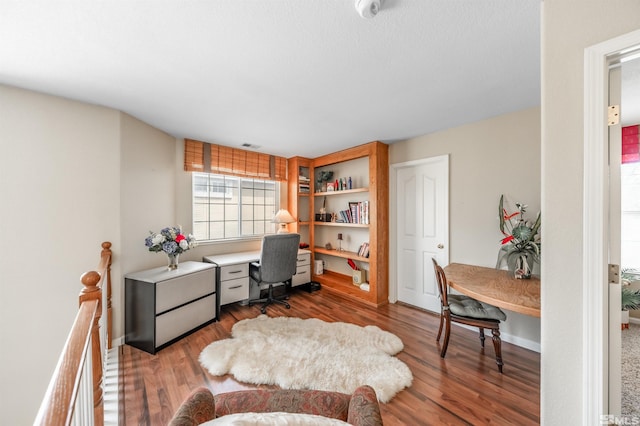 office space featuring baseboards, wood finished floors, and visible vents