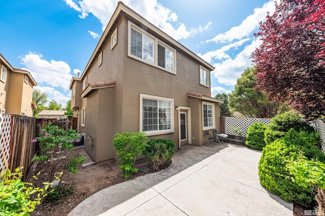 rear view of property featuring a fenced backyard, stucco siding, and a patio area