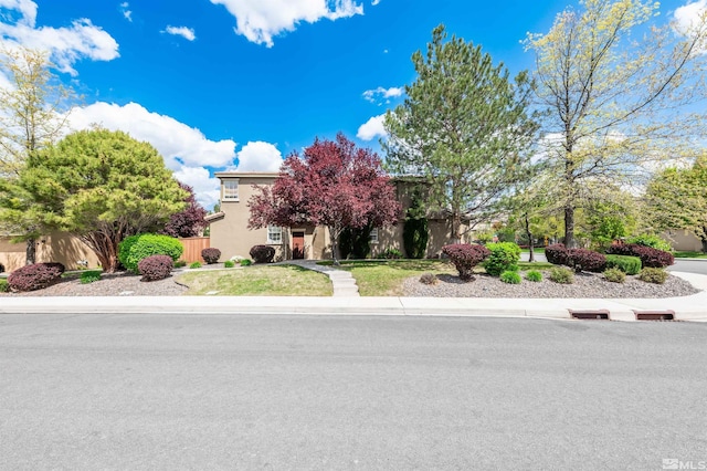 view of property hidden behind natural elements with fence and stucco siding