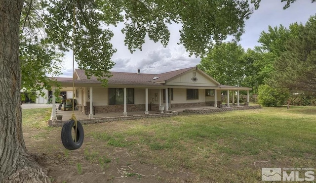 view of front of property with a shingled roof, covered porch, stone siding, and a front yard
