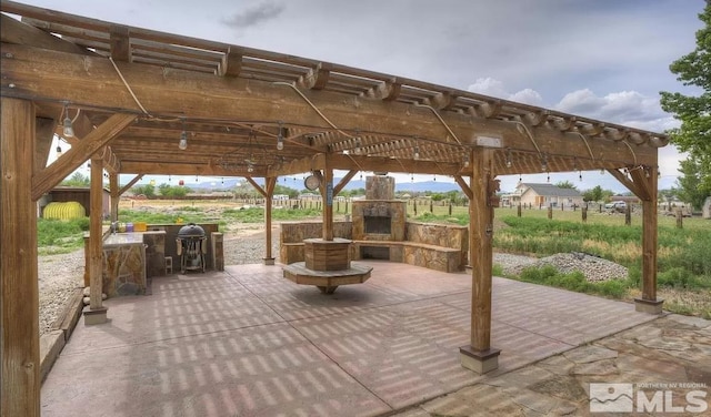 view of patio / terrace with an outdoor stone fireplace and a pergola