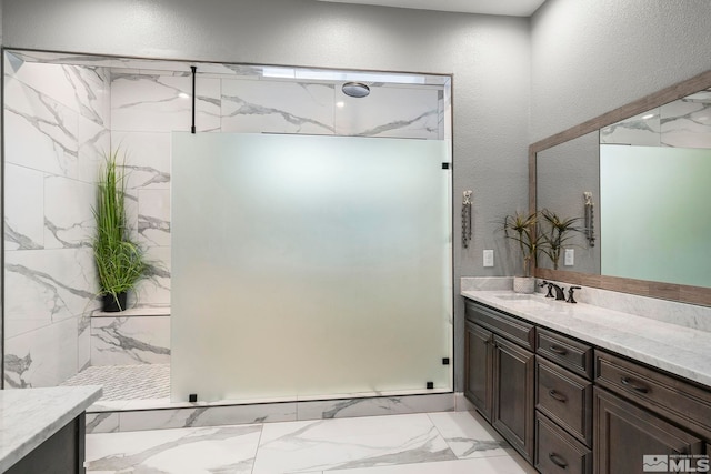 full bathroom featuring a textured wall, a marble finish shower, marble finish floor, and vanity