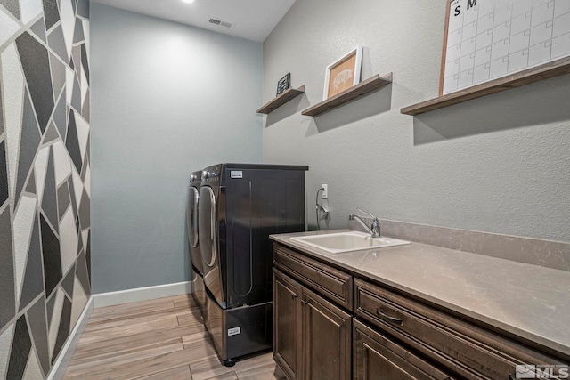 laundry room featuring independent washer and dryer, visible vents, a sink, and cabinet space