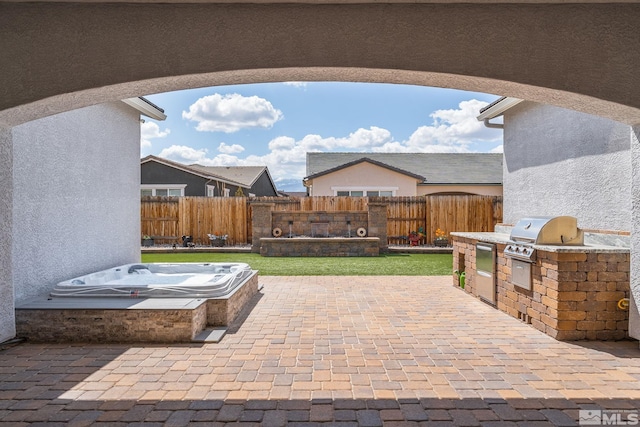 view of patio / terrace featuring an outdoor kitchen, fence, an outdoor hot tub, and grilling area