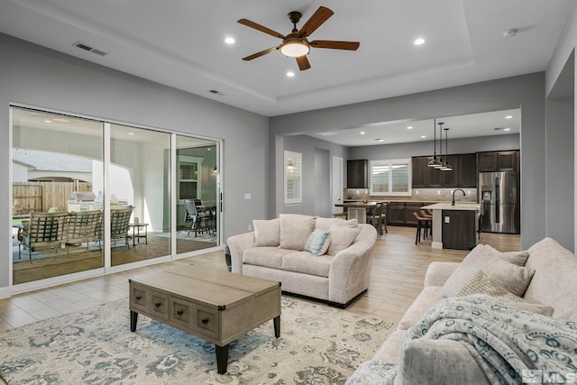 living room with recessed lighting, a ceiling fan, and a tray ceiling