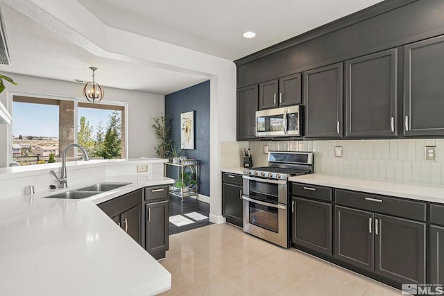 kitchen with a sink, appliances with stainless steel finishes, backsplash, and light countertops