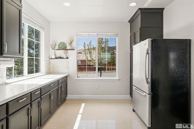 kitchen featuring light countertops, baseboards, light tile patterned floors, freestanding refrigerator, and recessed lighting