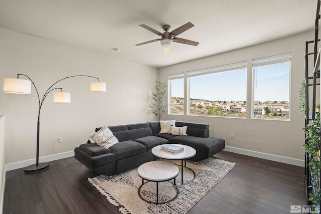 living area with baseboards, a ceiling fan, and dark wood-style flooring