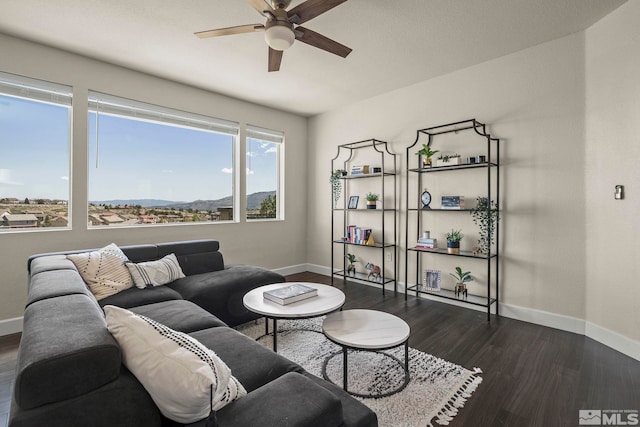 living area featuring baseboards, ceiling fan, and dark wood-style flooring