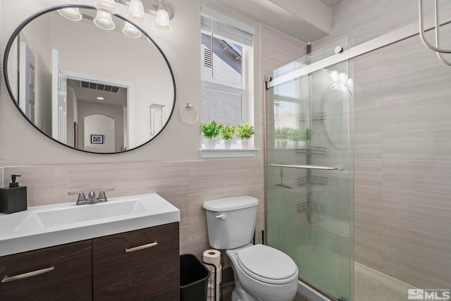 full bathroom featuring vanity, tile walls, toilet, and a shower stall