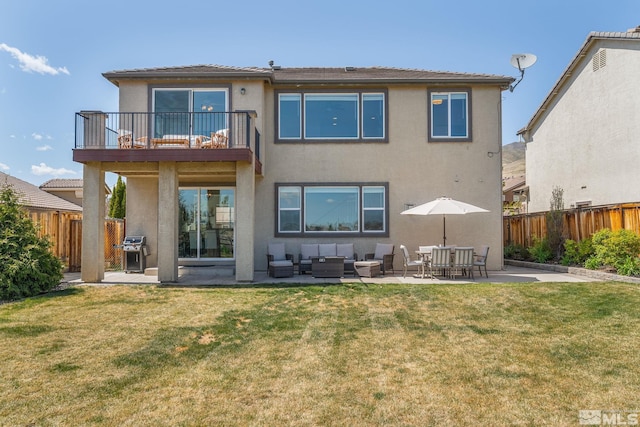 back of house with a balcony, a fenced backyard, stucco siding, an outdoor living space, and a patio area