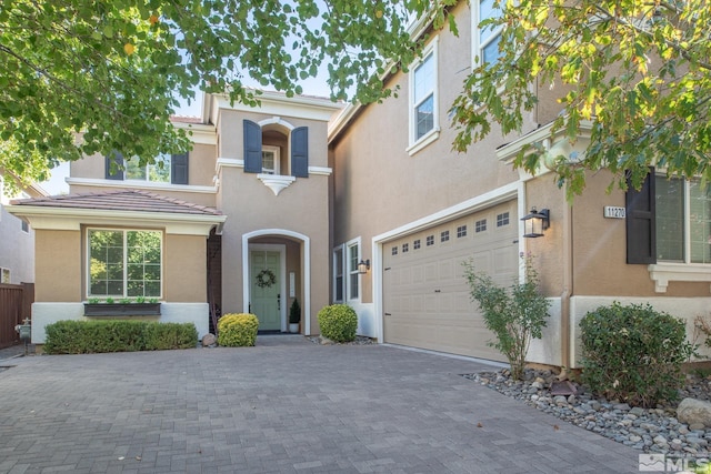 view of front of property featuring an attached garage, decorative driveway, and stucco siding