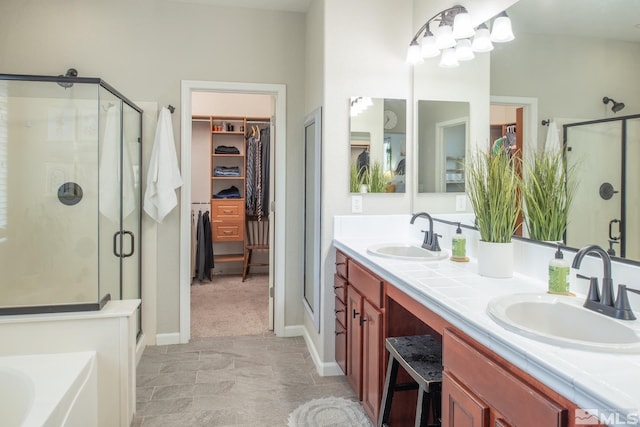 bathroom with double vanity, a sink, a stall shower, and a spacious closet