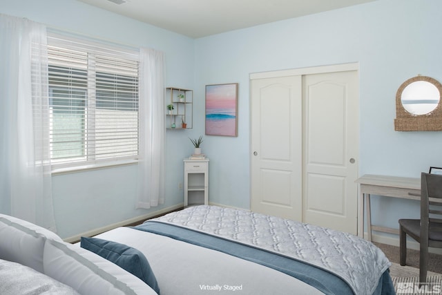 carpeted bedroom featuring baseboards and a closet