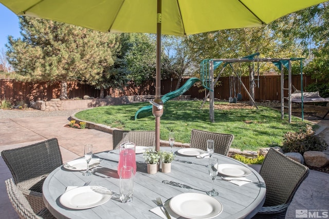 view of patio / terrace featuring a playground, outdoor dining space, a fenced backyard, and a wooden deck