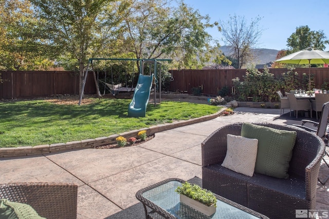 view of patio with a mountain view, a fenced backyard, and a playground