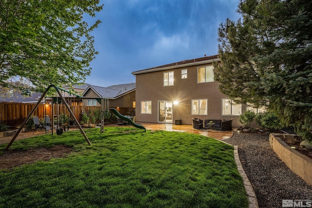 back of property featuring fence private yard, a patio, stucco siding, a playground, and a lawn