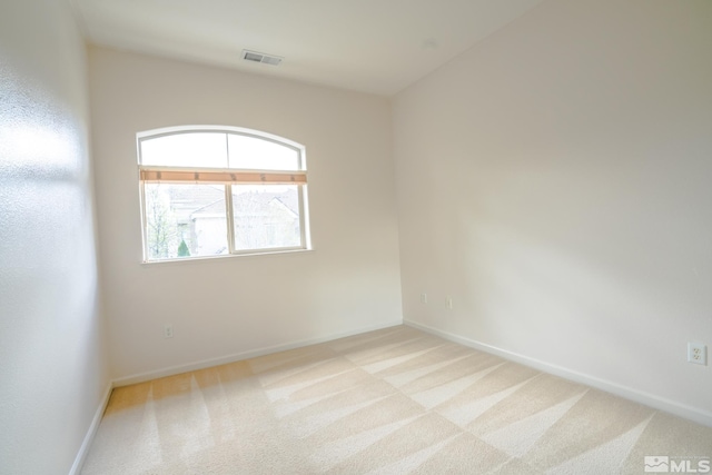 spare room featuring baseboards, light carpet, and visible vents