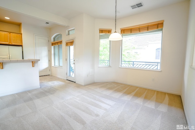 unfurnished dining area featuring visible vents, baseboards, and light colored carpet