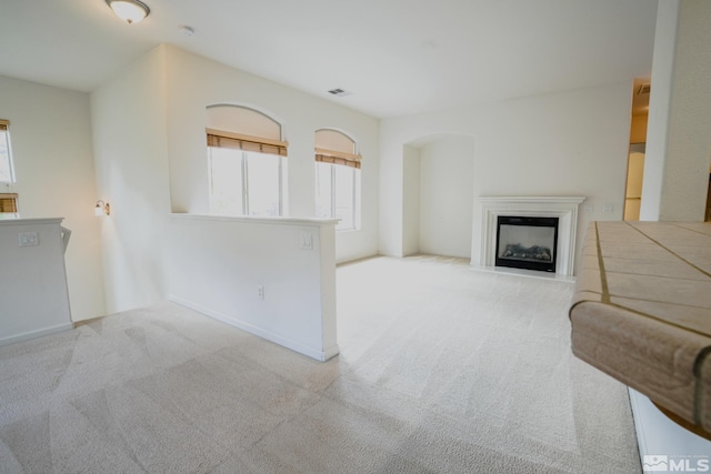 unfurnished living room with carpet flooring, visible vents, a wealth of natural light, and a fireplace