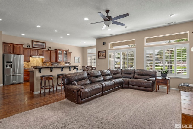 living room with visible vents, dark colored carpet, ceiling fan, recessed lighting, and a textured ceiling
