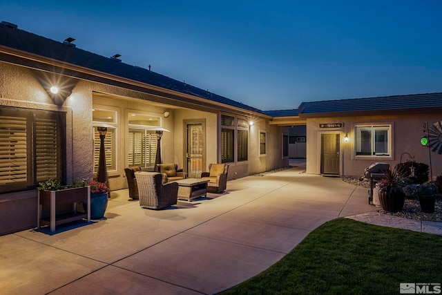 rear view of property featuring an outdoor hangout area, stucco siding, and a patio area