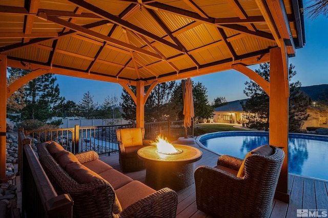 view of pool with a gazebo, an outdoor fire pit, a fenced in pool, and a deck
