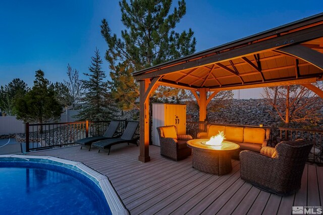 deck featuring a fenced in pool, a gazebo, and a fire pit