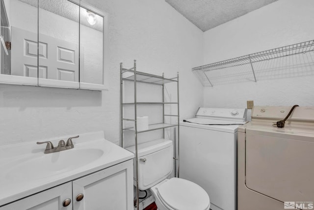 bathroom with a textured wall, vanity, toilet, a textured ceiling, and washing machine and dryer
