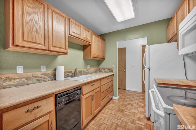 kitchen featuring white appliances, baseboards, a sink, and light brown cabinets